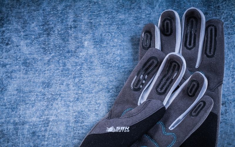 Hangi Standartlar? (EN 13594, EN ISO 21420 ve KP) CE’nin “hangi kurala göre” verildiğini anlamak için eldivenin iç etiketine bakarız. Motosiklet eldivenlerinin temel performans standardı EN 13594:2015’tir (Protective gloves for motorcycle riders). Bu standardın iki performans seviyesi vardır: Level 1: Daha az ergonomik kısıtlamayla temel koruma. Level 2: Daha yüksek koruma, fakat genellikle biraz daha hacim/ağırlık. Ayrıca KP (Knuckle Protection) ibaresi eklem/mafsal korumasının darbe testini geçtiğini gösterir. Level 2belgesi almak isteyen eldivenlerde knuckle darbe testi zorunludur; Level 1’de isteğe bağlıdır. Buna ek olarak tüm koruyucu eldivenler için geçerli genel gereklilik standardı EN ISO 21420:2020’dir (eski EN 420’nin yerini almıştır). Bu standart, tasarım–yapı, sağlığa zararsızlık (ör. kimyasal kısıtlar, pH, krom VI, DMFa), sezgisel konfor ve beden ölçüleri, işaretleme ve bilgi gibi yatay kuralları koyar. Kısaca: EN ISO 21420 “nasıl bir eldiven olmalı” sorusunu, EN 13594 ise “motosiklet kazasında nasıl korumalı” sorusunu yanıtlar. Hangi Standartlar? (EN 13594, EN ISO 21420 ve KP) CE’nin “hangi kurala göre” verildiğini anlamak için eldivenin iç etiketine bakarız. Motosiklet eldivenlerinin temel performans standardı EN 13594:2015’tir (Protective gloves for motorcycle riders). Bu standardın iki performans seviyesi vardır: Level 1: Daha az ergonomik kısıtlamayla temel koruma. Level 2: Daha yüksek koruma, fakat genellikle biraz daha hacim/ağırlık. Ayrıca KP (Knuckle Protection) ibaresi eklem/mafsal korumasının darbe testini geçtiğini gösterir. Level 2belgesi almak isteyen eldivenlerde knuckle darbe testi zorunludur; Level 1’de isteğe bağlıdır. Buna ek olarak tüm koruyucu eldivenler için geçerli genel gereklilik standardı EN ISO 21420:2020’dir (eski EN 420’nin yerini almıştır). Bu standart, tasarım–yapı, sağlığa zararsızlık (ör. kimyasal kısıtlar, pH, krom VI, DMFa), sezgisel konfor ve beden ölçüleri, işaretleme ve bilgi gibi yatay kuralları koyar. Kısaca: EN ISO 21420 “nasıl bir eldiven olmalı” sorusunu, EN 13594 ise “motosiklet kazasında nasıl korumalı” sorusunu yanıtlar.